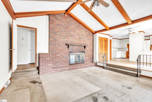 unfurnished living room with ceiling fan, lofted ceiling with beams, a brick fireplace, and light colored carpet