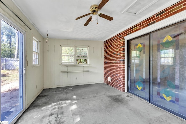 unfurnished sunroom featuring ceiling fan