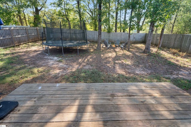 view of yard featuring a trampoline and a deck