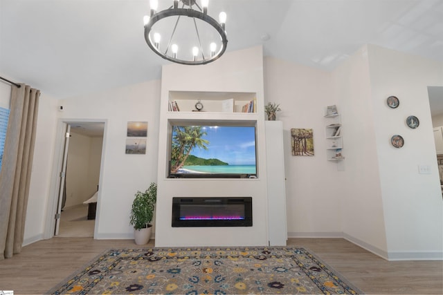 living room with a notable chandelier, light wood-type flooring, and vaulted ceiling