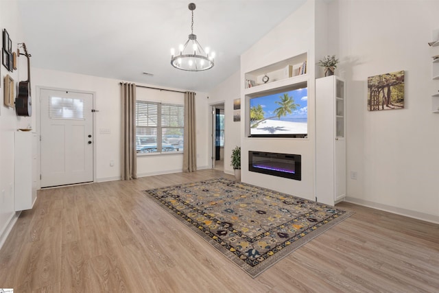 living room featuring a notable chandelier, built in features, vaulted ceiling, and light hardwood / wood-style flooring