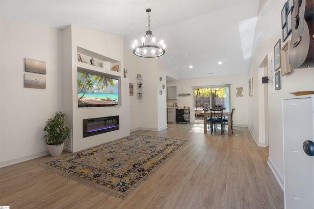 living room with light wood-type flooring, lofted ceiling, and an inviting chandelier