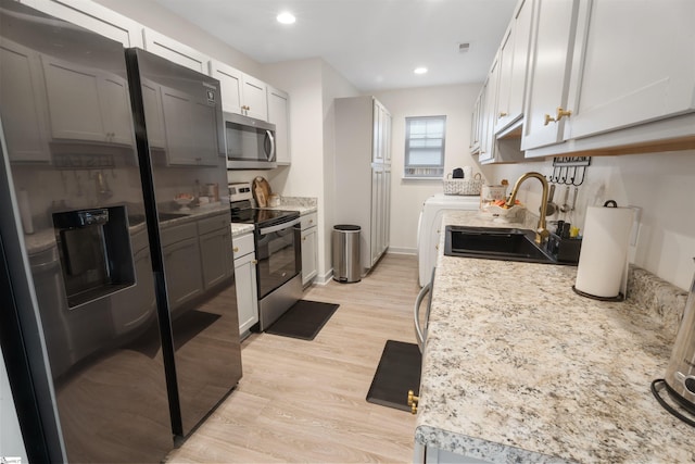 kitchen with appliances with stainless steel finishes, sink, light wood-type flooring, and white cabinetry