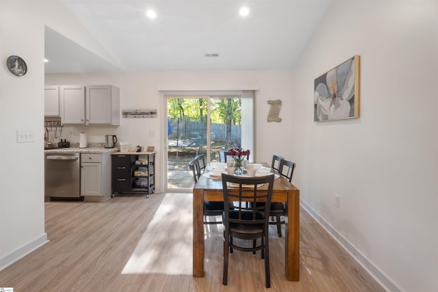 dining area with light wood-type flooring and vaulted ceiling