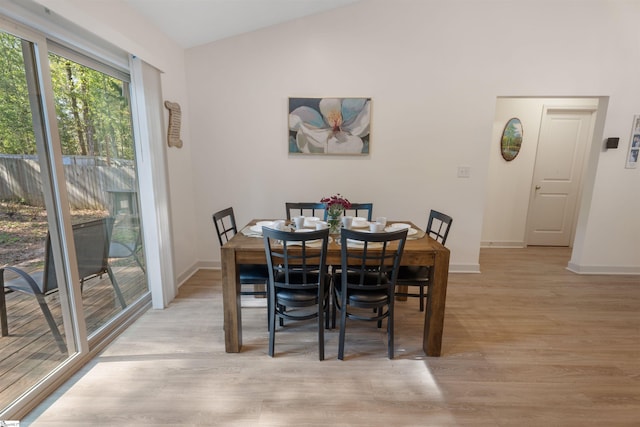 dining space featuring vaulted ceiling and light hardwood / wood-style flooring