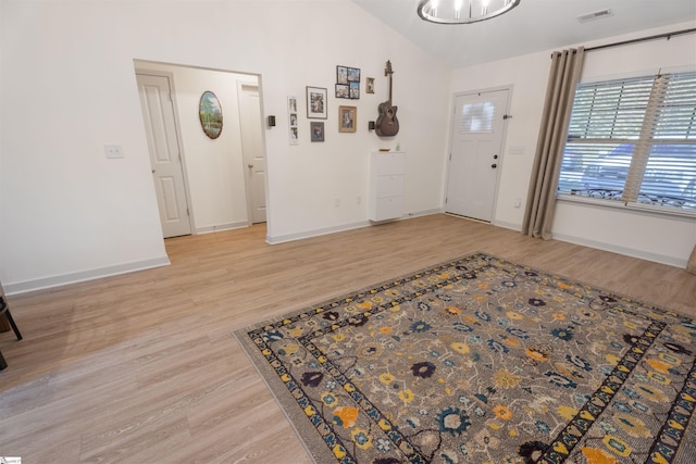 foyer featuring an inviting chandelier, light hardwood / wood-style flooring, and vaulted ceiling