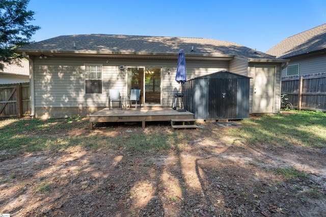 rear view of property featuring a deck and a storage shed