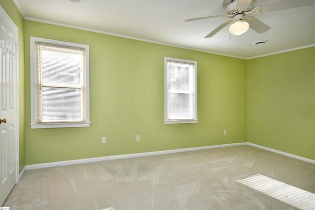 carpeted empty room featuring ceiling fan, ornamental molding, and a healthy amount of sunlight