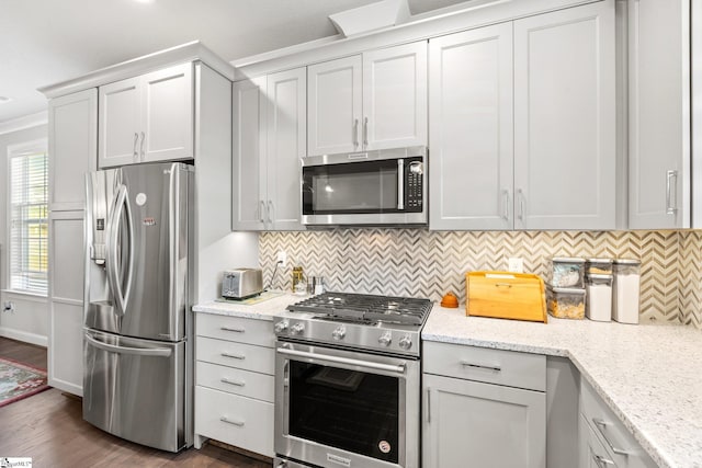 kitchen featuring light stone counters, decorative backsplash, dark hardwood / wood-style floors, ornamental molding, and appliances with stainless steel finishes