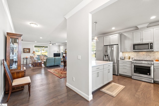 kitchen with ceiling fan, pendant lighting, ornamental molding, dark wood-type flooring, and appliances with stainless steel finishes