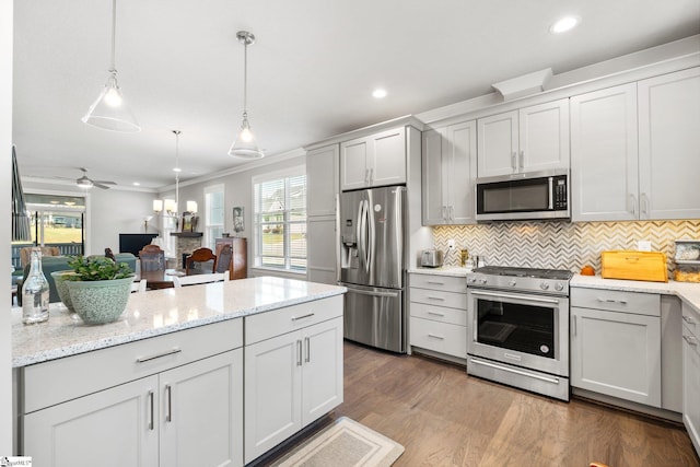 kitchen with ceiling fan, ornamental molding, decorative light fixtures, hardwood / wood-style flooring, and stainless steel appliances