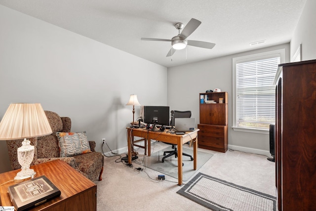 carpeted home office with ceiling fan and a textured ceiling