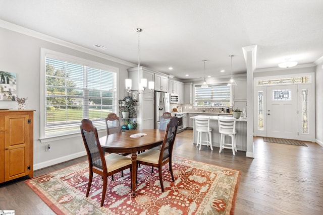 dining room with hardwood / wood-style flooring, crown molding, and a chandelier