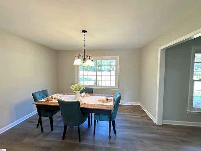 dining area featuring dark wood-type flooring and an inviting chandelier