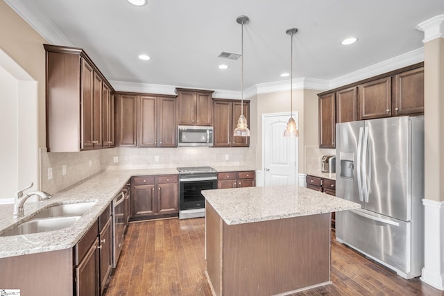 kitchen with a kitchen island, dark hardwood / wood-style floors, sink, hanging light fixtures, and appliances with stainless steel finishes