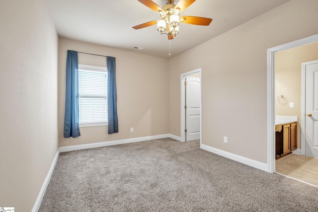 unfurnished bedroom featuring ceiling fan, ensuite bathroom, and light carpet