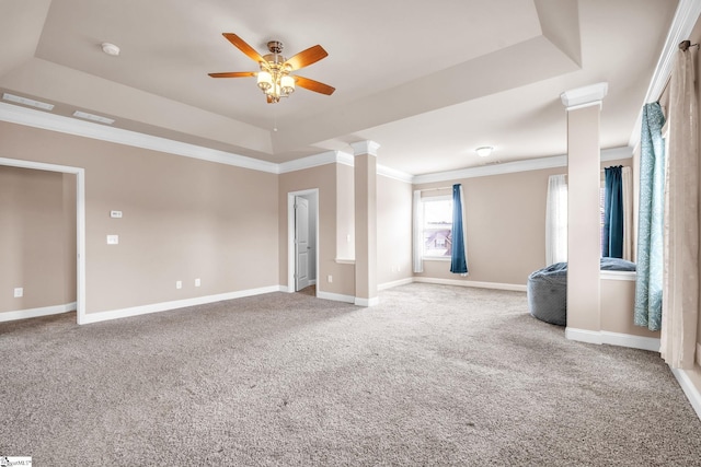 unfurnished living room featuring a raised ceiling, ornate columns, carpet floors, and crown molding