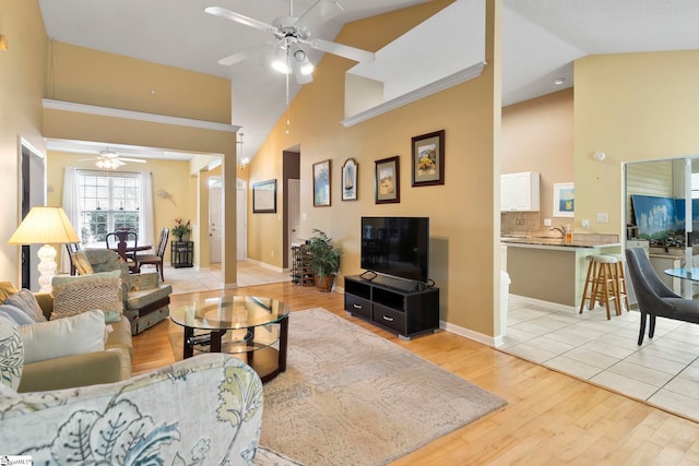 living room with ceiling fan, light hardwood / wood-style floors, and high vaulted ceiling