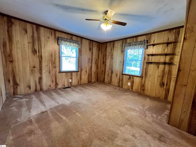 empty room featuring carpet floors, wooden walls, and ceiling fan