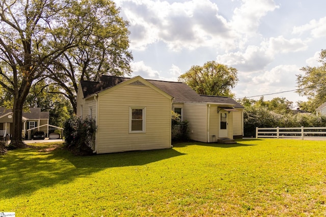 back of property with a carport and a lawn