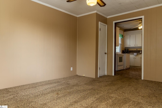 spare room with carpet floors, wooden walls, crown molding, and ceiling fan