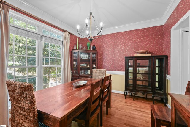 dining space with a notable chandelier, crown molding, and light hardwood / wood-style floors