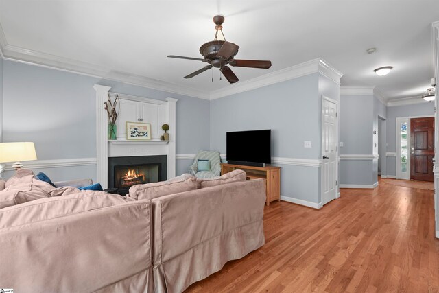 living room with ceiling fan, light wood-type flooring, and ornamental molding