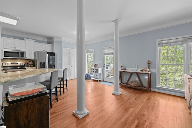 kitchen featuring stainless steel appliances, ornamental molding, a healthy amount of sunlight, and white cabinetry