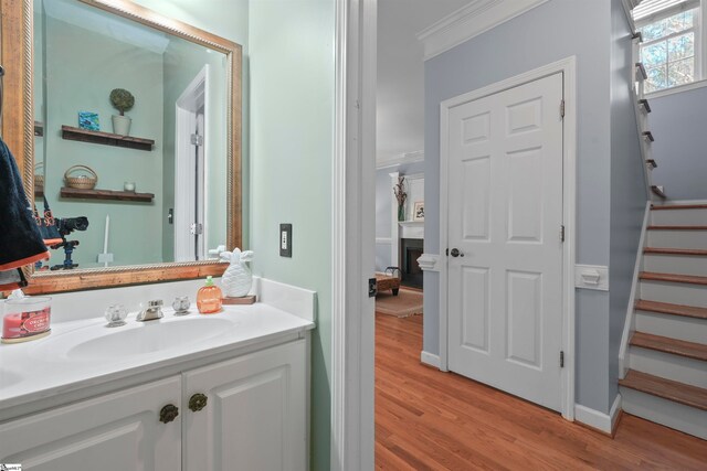 bathroom with vanity, crown molding, and hardwood / wood-style flooring