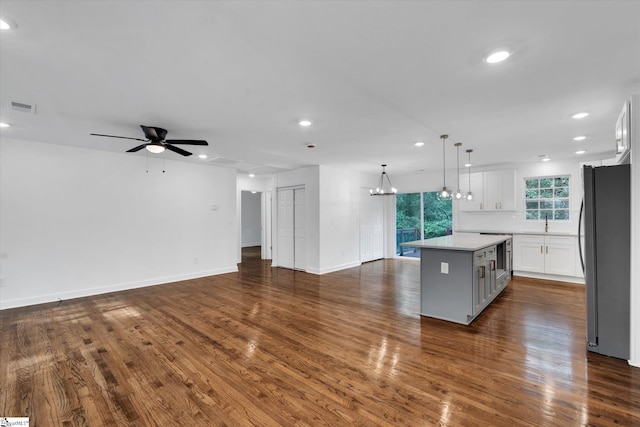 kitchen featuring hanging light fixtures, white cabinetry, stainless steel refrigerator, dark hardwood / wood-style floors, and a center island