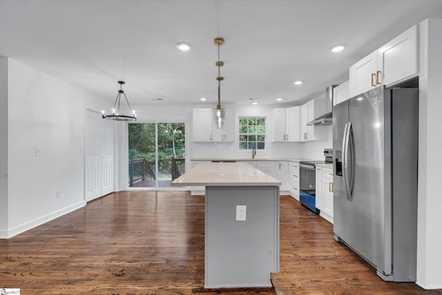 kitchen with white cabinets, decorative light fixtures, stainless steel appliances, dark hardwood / wood-style floors, and a center island