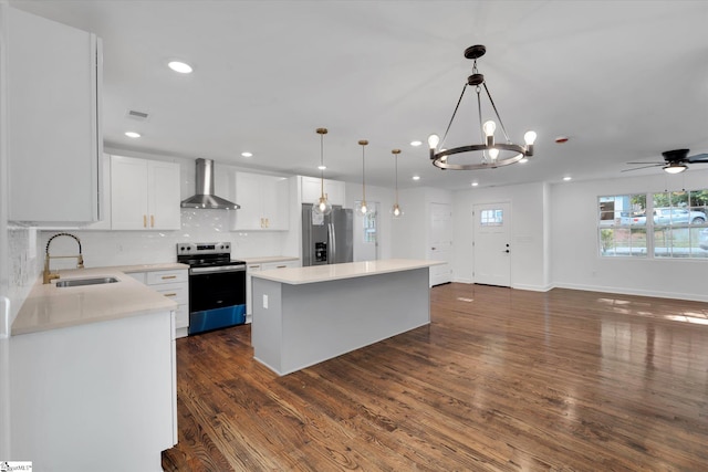 kitchen with hanging light fixtures, sink, wall chimney range hood, stainless steel appliances, and a center island