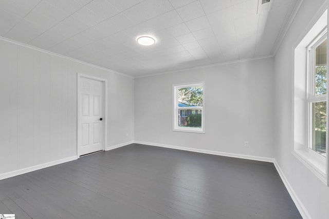 empty room with plenty of natural light, dark hardwood / wood-style flooring, and crown molding