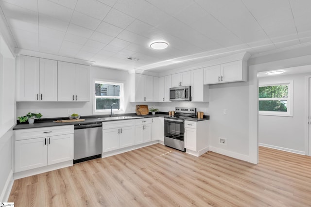 kitchen with light wood-type flooring, white cabinets, and stainless steel appliances