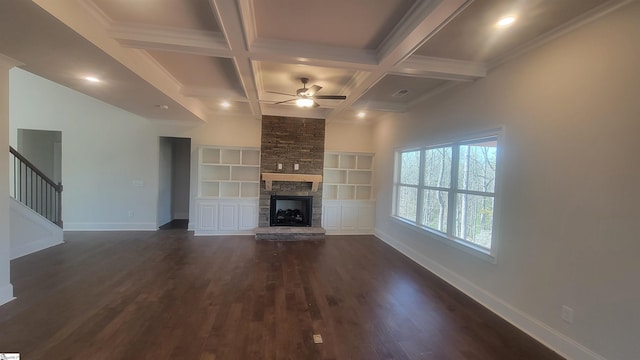 unfurnished living room featuring dark wood finished floors, stairway, a stone fireplace, coffered ceiling, and baseboards