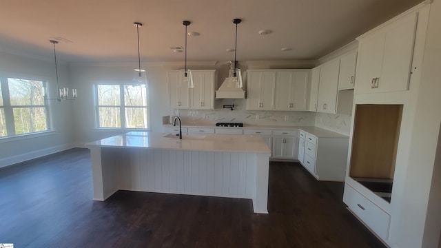 kitchen featuring hanging light fixtures, an island with sink, white cabinetry, and custom range hood