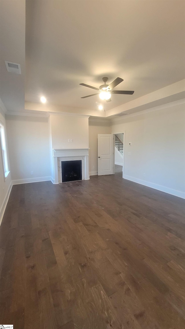 unfurnished living room with a fireplace, dark wood finished floors, visible vents, and baseboards