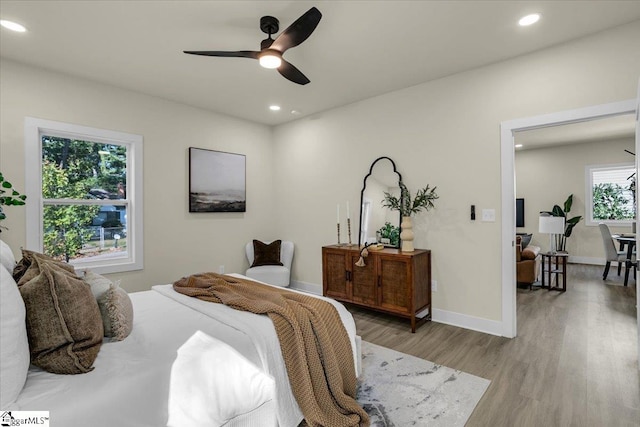 bedroom with light wood-type flooring, multiple windows, and ceiling fan