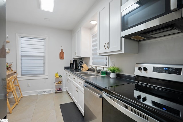 kitchen featuring stainless steel appliances, sink, light tile patterned floors, and white cabinetry