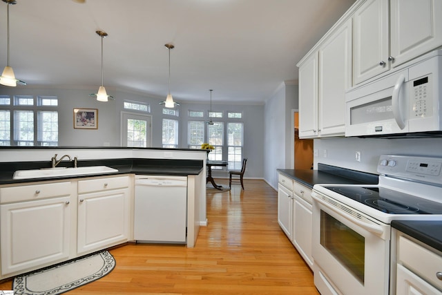 kitchen with hanging light fixtures, sink, white appliances, white cabinetry, and light wood-type flooring