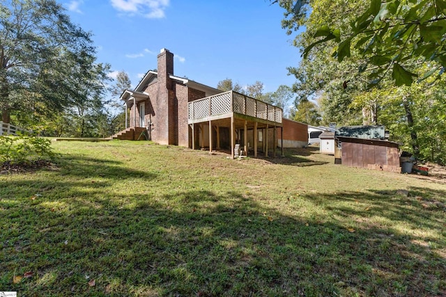 rear view of property with a yard, a deck, and a storage shed