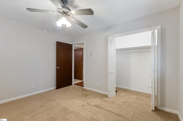 unfurnished bedroom with a closet, light colored carpet, and ceiling fan