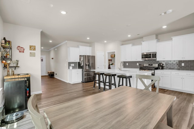 dining area with crown molding, sink, and light wood-type flooring