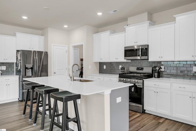 kitchen with white cabinets, sink, wood-type flooring, a kitchen island with sink, and stainless steel appliances