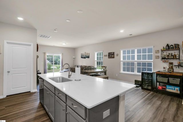 kitchen featuring dark hardwood / wood-style floors, sink, a center island with sink, gray cabinets, and dishwasher