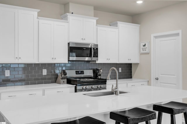 kitchen featuring appliances with stainless steel finishes, sink, a kitchen breakfast bar, and tasteful backsplash