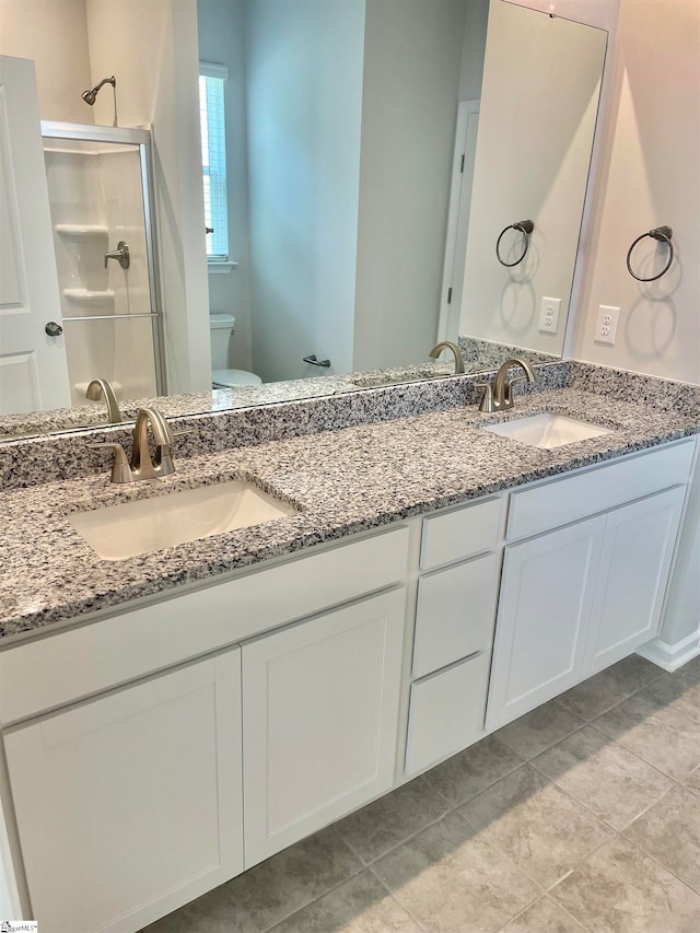 bathroom with a shower with door, tile patterned floors, vanity, and toilet