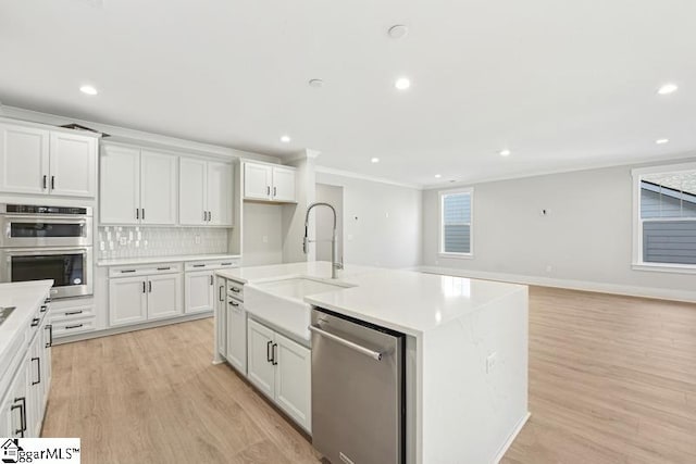 kitchen with white cabinets, sink, stainless steel appliances, and a kitchen island with sink