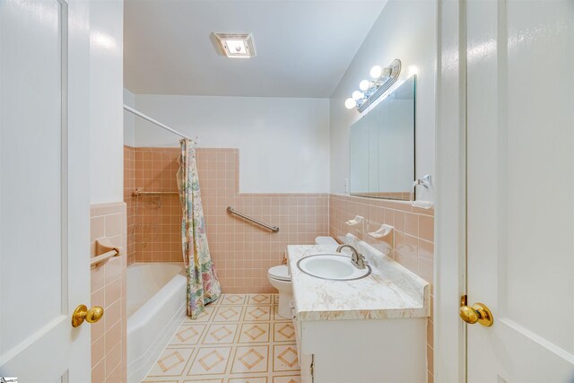 full bathroom featuring vanity, tile walls, toilet, and shower / bath combo