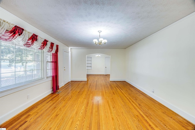 empty room featuring hardwood / wood-style floors, a notable chandelier, and a textured ceiling